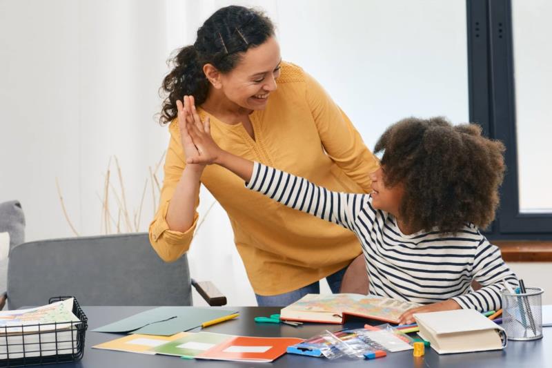 Family child care provider high fives a young child in a home-based child care program
